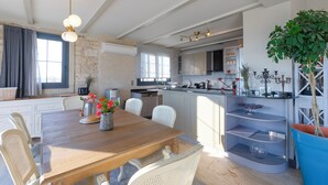 Una cocina amplia con armarios blancos, una mesa de comedor de madera y un ventanal grande.