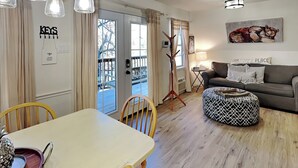 Un salon chaleureux avec un canapé, un pouf à motifs, une table à manger avec des chaises et un lustre.