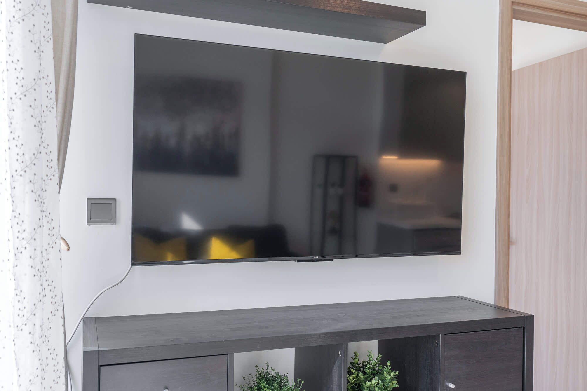 A flat-screen TV mounted on a wall above a dark wooden console.