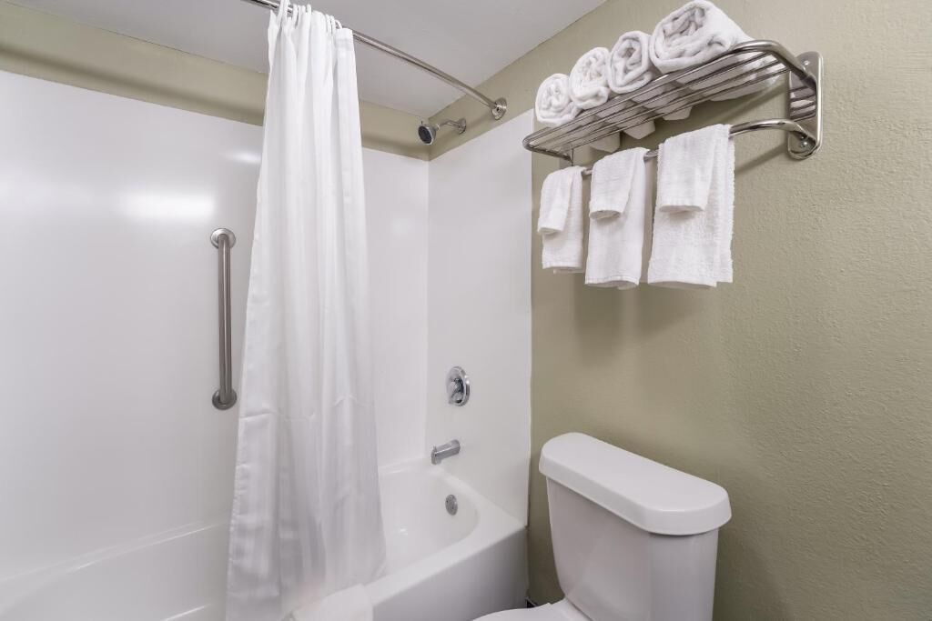 A bathroom with a bathtub, a toilet, and a towel rack with neatly folded towels.