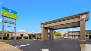 A SureStay by Best Western hotel entrance with a clear sky, a parking lot, and a covered walkway. - We in Heart DownTown of Columbus and Fort Moore (Columbus)
