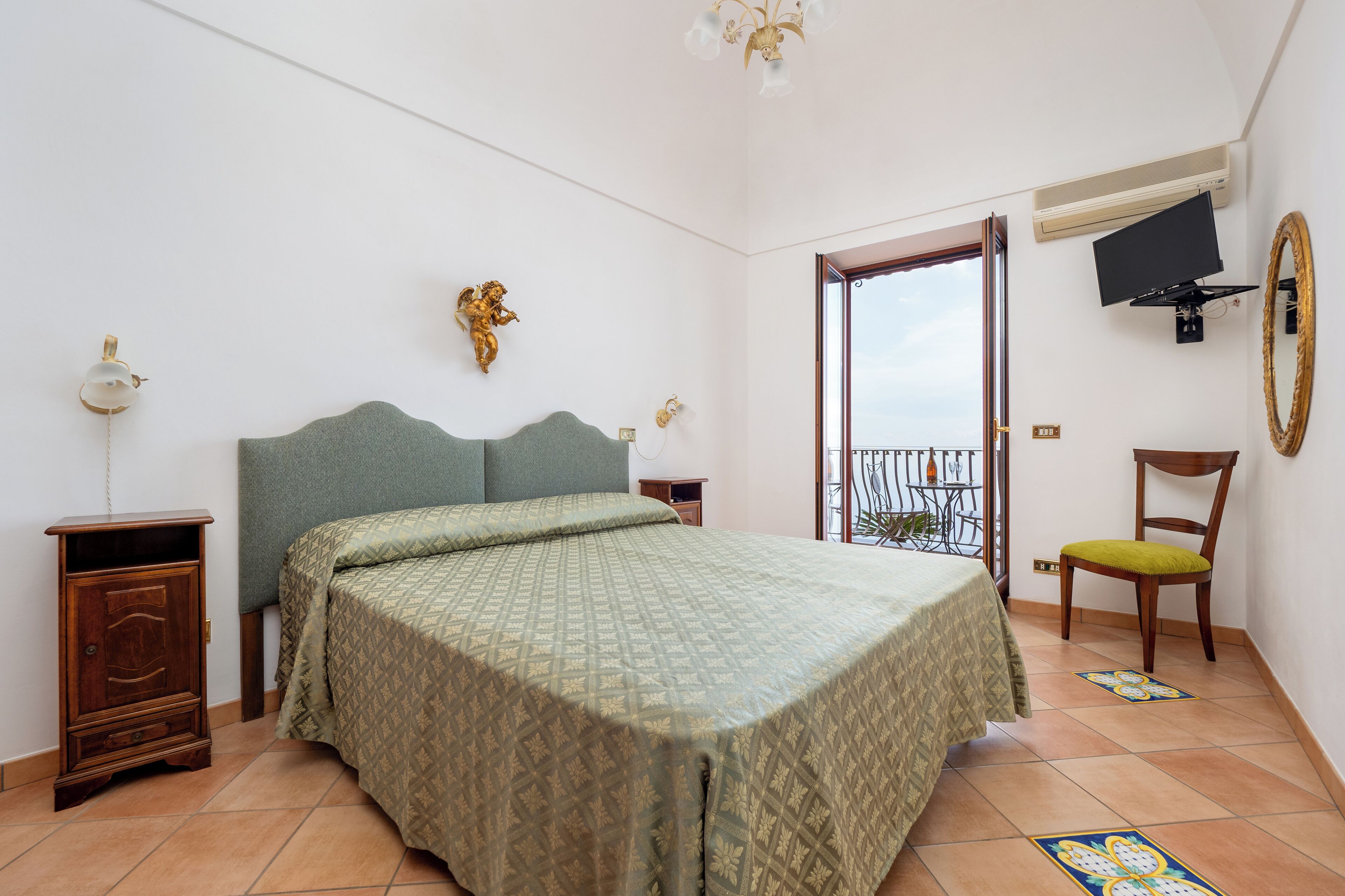 A bedroom with a bed, a wooden cabinet, a chair, a television, and a balcony door.
