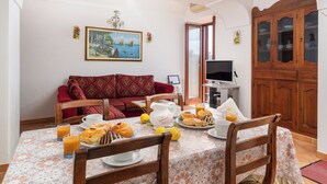 A dining area with a table set for breakfast, a sofa, and a cabinet. - Villa Lavinia (Positano)