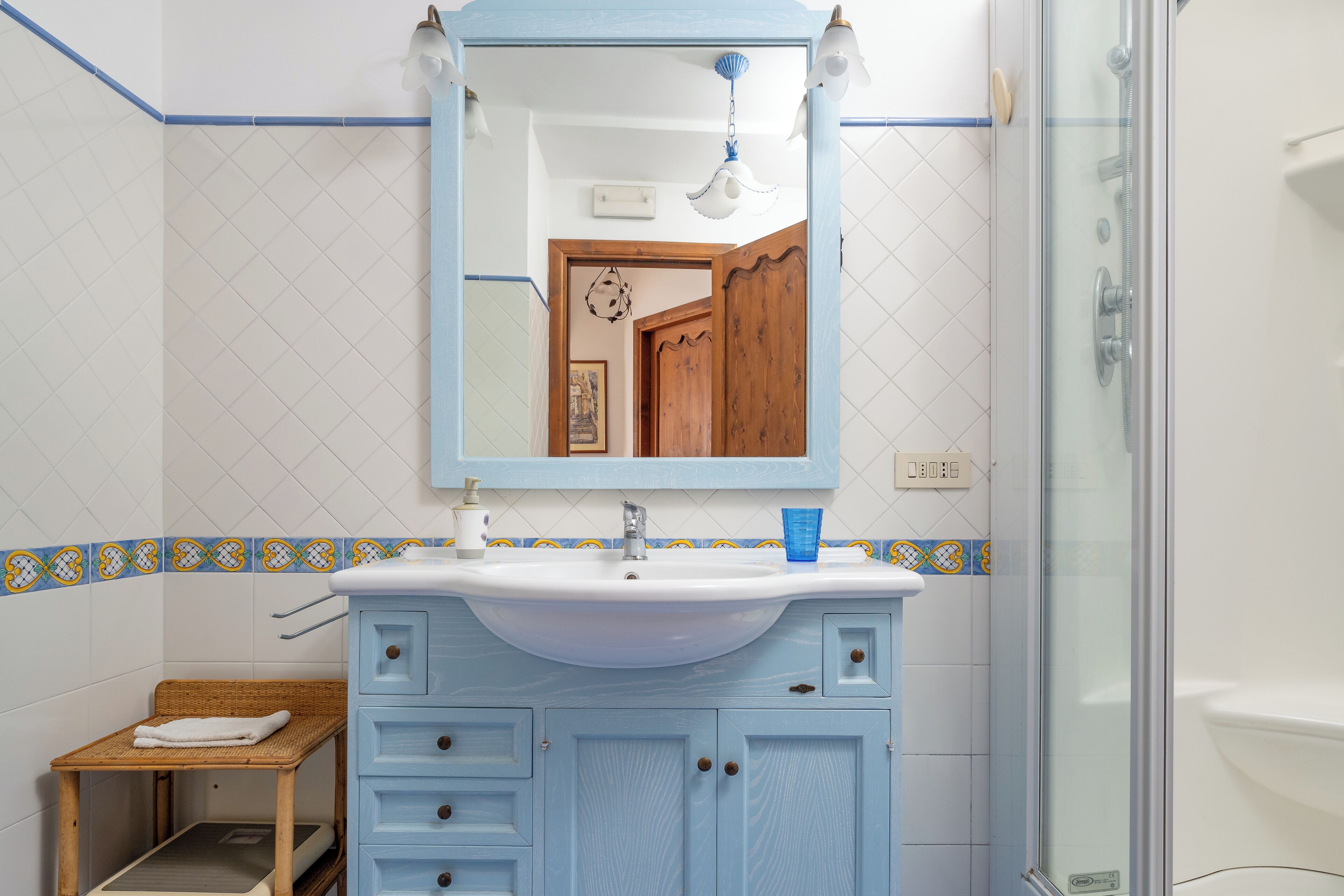 A bathroom with a blue vanity, a sink, and a mirror.