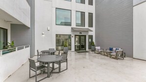 Een moderne buitenpatio met een zithoek en een toegang tot het gebouw.