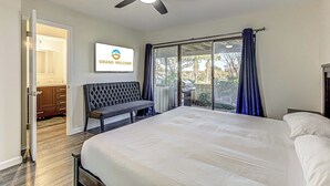 A bedroom with a bed, a ceiling fan, a bench, a sliding glass door, and a 'Grand Welcome' sign. - Cozy 3 BDR Condo in Horseshoe Bay, Near Marina! (Horseshoe Bay)