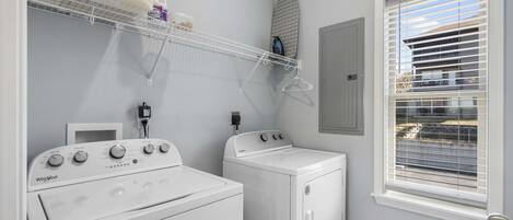Un cuarto de lavado con lavadora y secadora Whirlpool, un tendedero y una ventana con persianas.