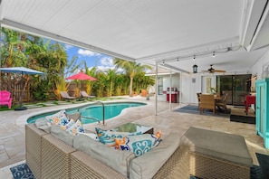 A covered outdoor area with a swimming pool, lounge chairs, and a dining area. - Heated Pool ,Mini Golf, Game Room, Near Beaches (Bradenton)
