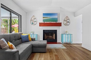 Un salon moderne avec un canapé d’angle, une cheminée et un grand écran de télévision placé au-dessus.