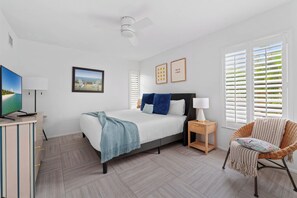 A bedroom with a bed, a television, a chair, and a ceiling fan. - Heated Pool ,Mini Golf, Game Room, Near Beaches (Bradenton)
