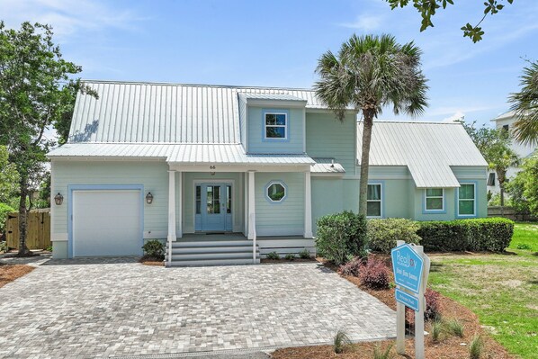 A two-story house with a blue door, a garage, and a front porch.