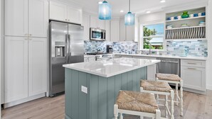 A modern kitchen with white cabinetry, a central island, stainless steel appliances, and blue pendant lights. - ☀️Charming 30A Home with Private Pool-Short Walk to Beach-Jini Jim Jams☀️ (Santa Rosa Beach)