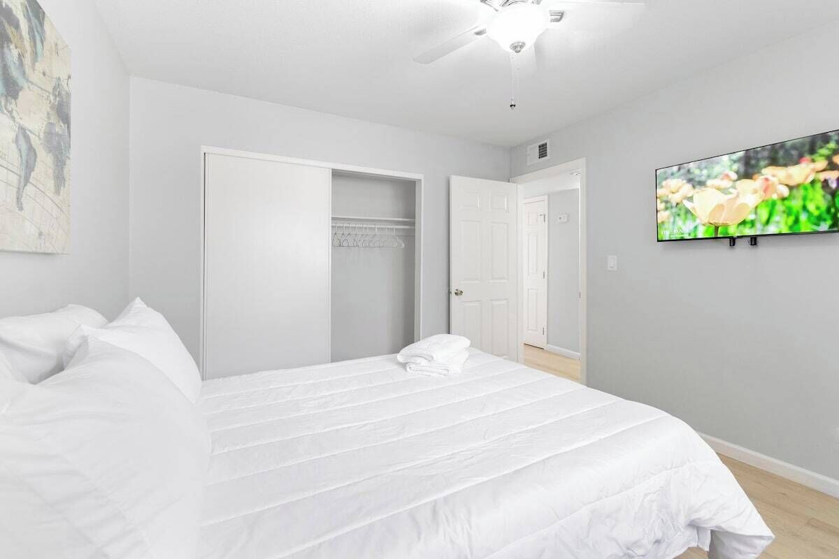 A bedroom with a bed, a ceiling fan, a television, and a wardrobe.