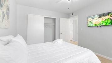 A bedroom with a bed, a ceiling fan, a television, and a wardrobe.
