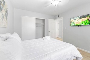 Ein Schlafzimmer mit einem Bett, einem Deckenventilator, einem Fernseher und einem Kleiderschrank.