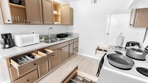 A compact kitchen with wooden cabinets, a microwave, a sink, and a stove.