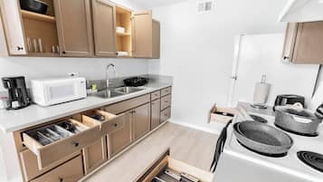 A compact kitchen with wooden cabinets, a microwave, a sink, and a stove.