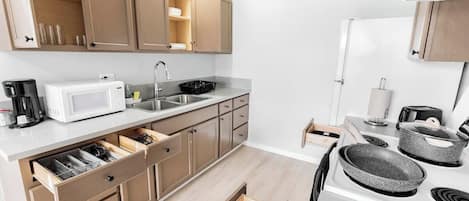 Une cuisine de taille réduite, dotée de meubles en bois, d’un four à micro-ondes, d’un évier et d’une cuisinière.