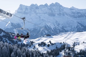 A ski lift with skiers in colorful jackets, a snowy mountain landscape, and a clear sky. - Chalet in La Béchigne with Valley Views (Châtel)