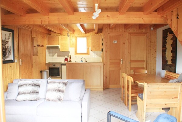A wooden cabin interior with a sofa, dining table, and kitchen area. - Chalet in La Béchigne with Valley Views (Châtel)