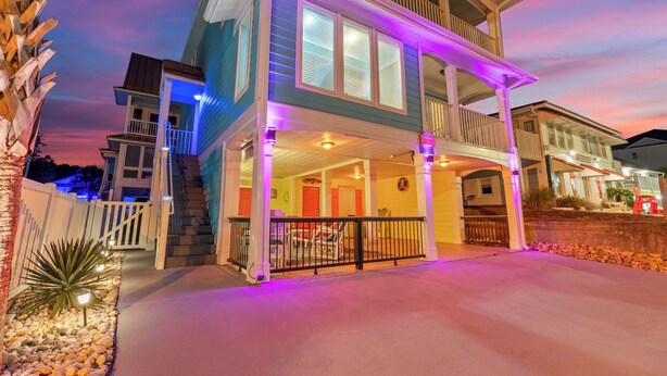 A two-story house with a balcony, a porch, and a staircase leading to the upper floor. - A Little Piece Of Heaven-5BR-2nd Row-Pet Friendly (North Myrtle Beach)