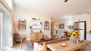 Amplia sala de estar con una mesa de comedor, asientos cómodos, una cocina con electrodomésticos modernos y un gran ventanal que proporciona luz natural.