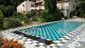 A pool with a checkered pattern, surrounded by greenery and a building with a stone facade. - Detached south-facing studio with swimming pool, property overlooking Toulon harbour  (Toulon)