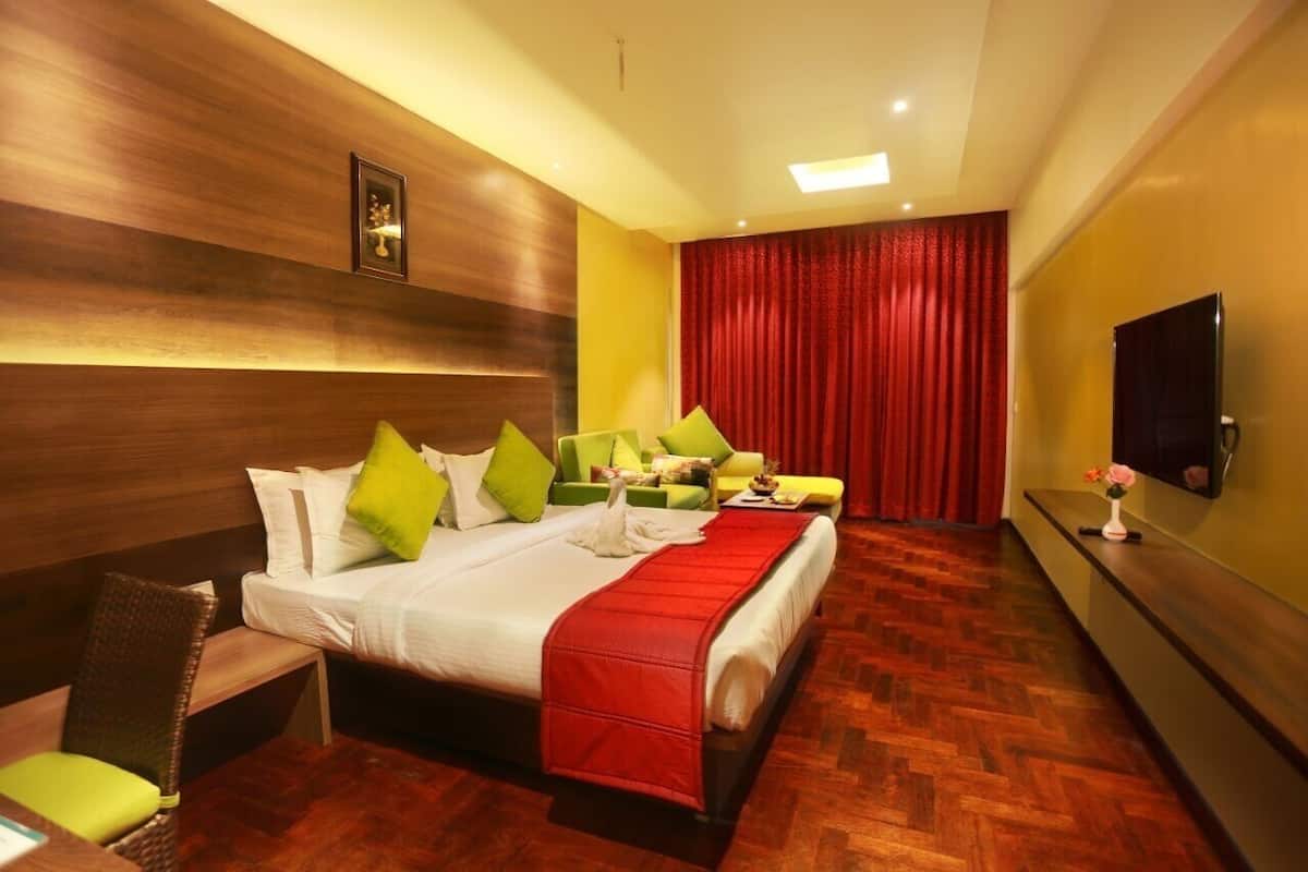 A hotel room with a bed, a desk, a chair, a TV, and a red curtain.