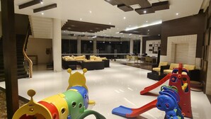 A spacious living area with a modern staircase, a seating area with sofas, and a play area with colorful toys.