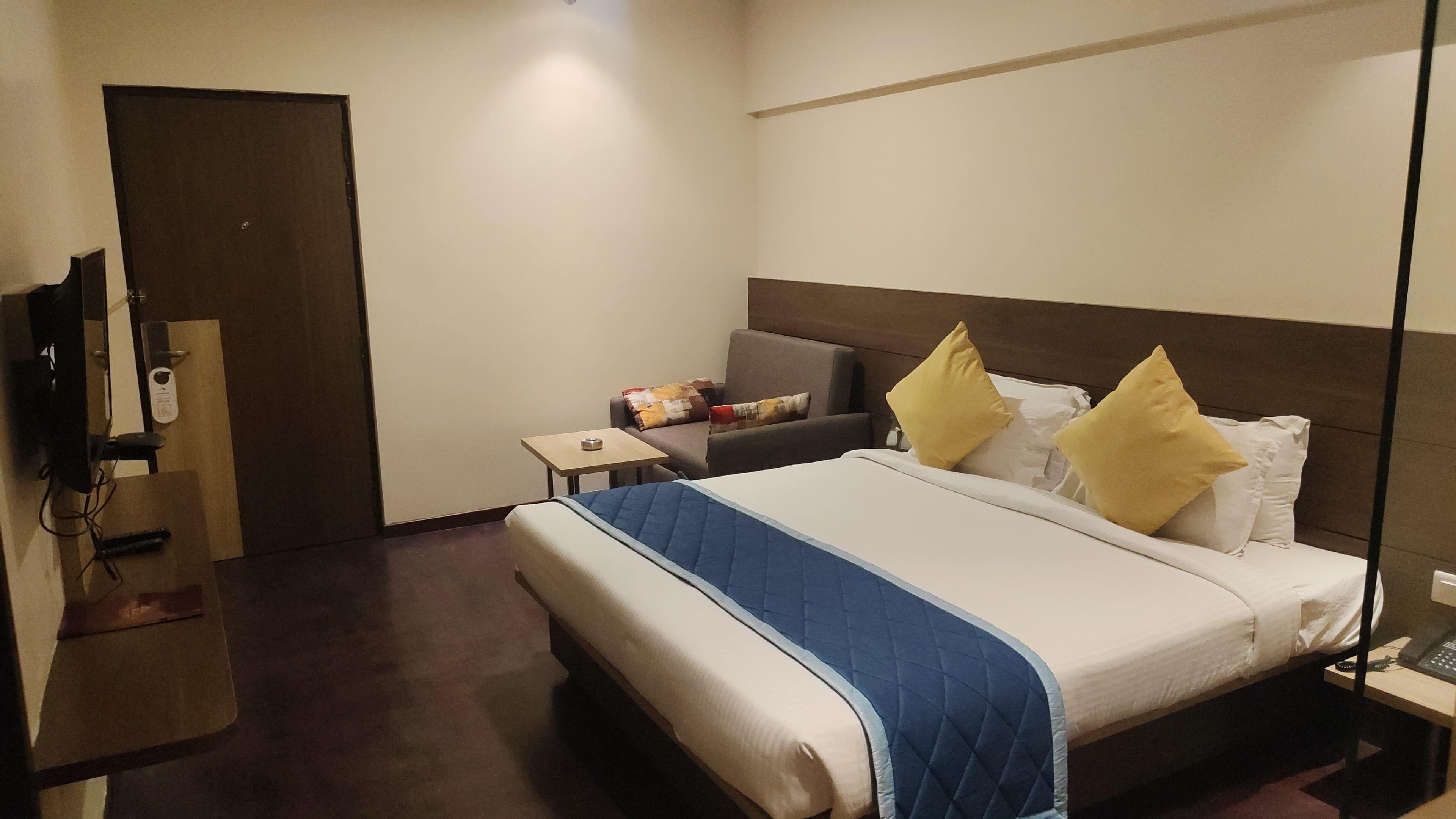 Una habitación de hotel con cama, mesita de noche y televisión.