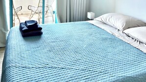 Habitación de hotel con cama, ventana con cortinas, radiador y una silla.