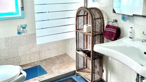 Un baño con ducha, inodoro, lavabo y un estante decorativo.