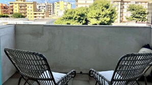 Un balcón con dos sillas de mimbre y una pared de hormigón.