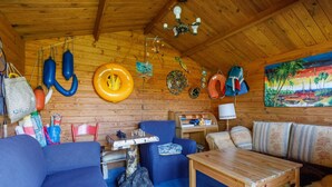 A wooden interior with a blue sofa, a wooden table, and a painting of a tropical scene.