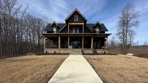 A large, two-story house with a prominent front porch and a long driveway leading to it. - Stunning 4-bedroom house with amazing outdoor space and dock in Double Springs. (Double Springs)
