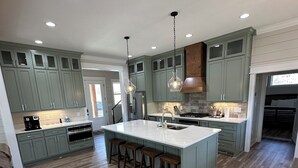 A spacious kitchen with a large island, wooden flooring, and green cabinets. - Stunning 4-bedroom house with amazing outdoor space and dock in Double Springs. (Double Springs)