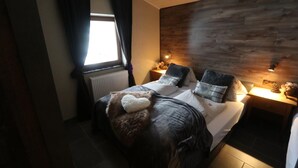 A bedroom with a bed, a nightstand, a lamp, and a window. - Apartment Haus Tauern Am See  (Heiterwang)