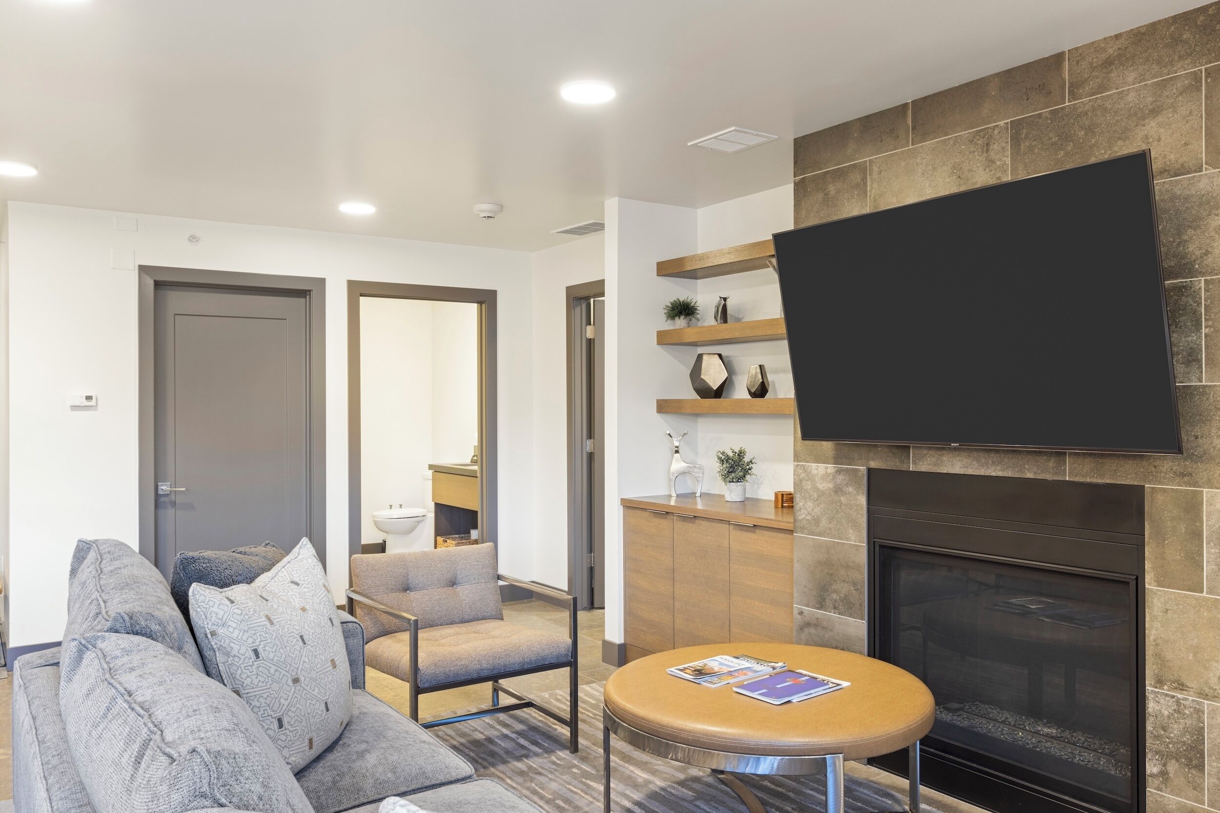 A modern living room with a grey sofa, a round coffee table, and a fireplace.
