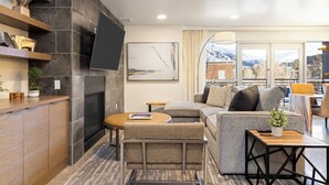Una sala de estar moderna con chimenea, un sofá, una mesa de centro y un televisor montado en la pared.