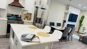 A modern kitchen with a central island, stainless steel appliances, and a dining area with a table and chairs. - Spacious 3Story,3bedroom,Pets Park,Near UofA&more attractions.Luxury starts here (Edmonton)