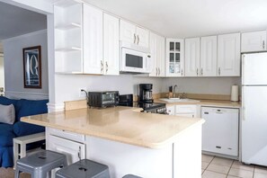 A modern kitchen with white cabinets, a microwave, a coffee maker, and a dishwasher.