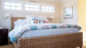 A bedroom with a woven headboard, floral bedding, two bedside lamps, and a framed picture on the wall. - Spectacular View from Rooftop Deck | Sleeps 12 (Middletown)