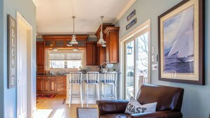 A modern kitchen with wooden cabinets, a bar area with stools, and a leather sofa with a cushion. - Spectacular View from Rooftop Deck | Sleeps 12 (Middletown)