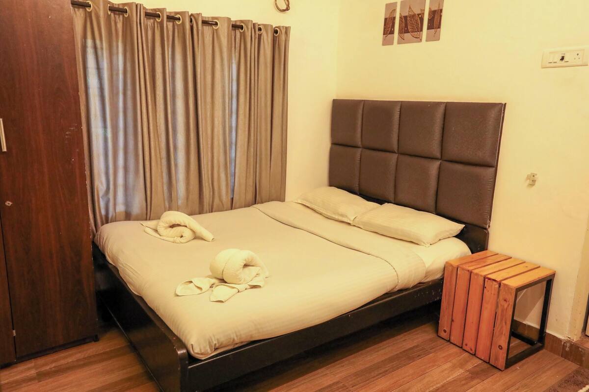 Cama bem arrumada com cabeceira, mesa de cabeceira de madeira e guarda-roupa de madeira.