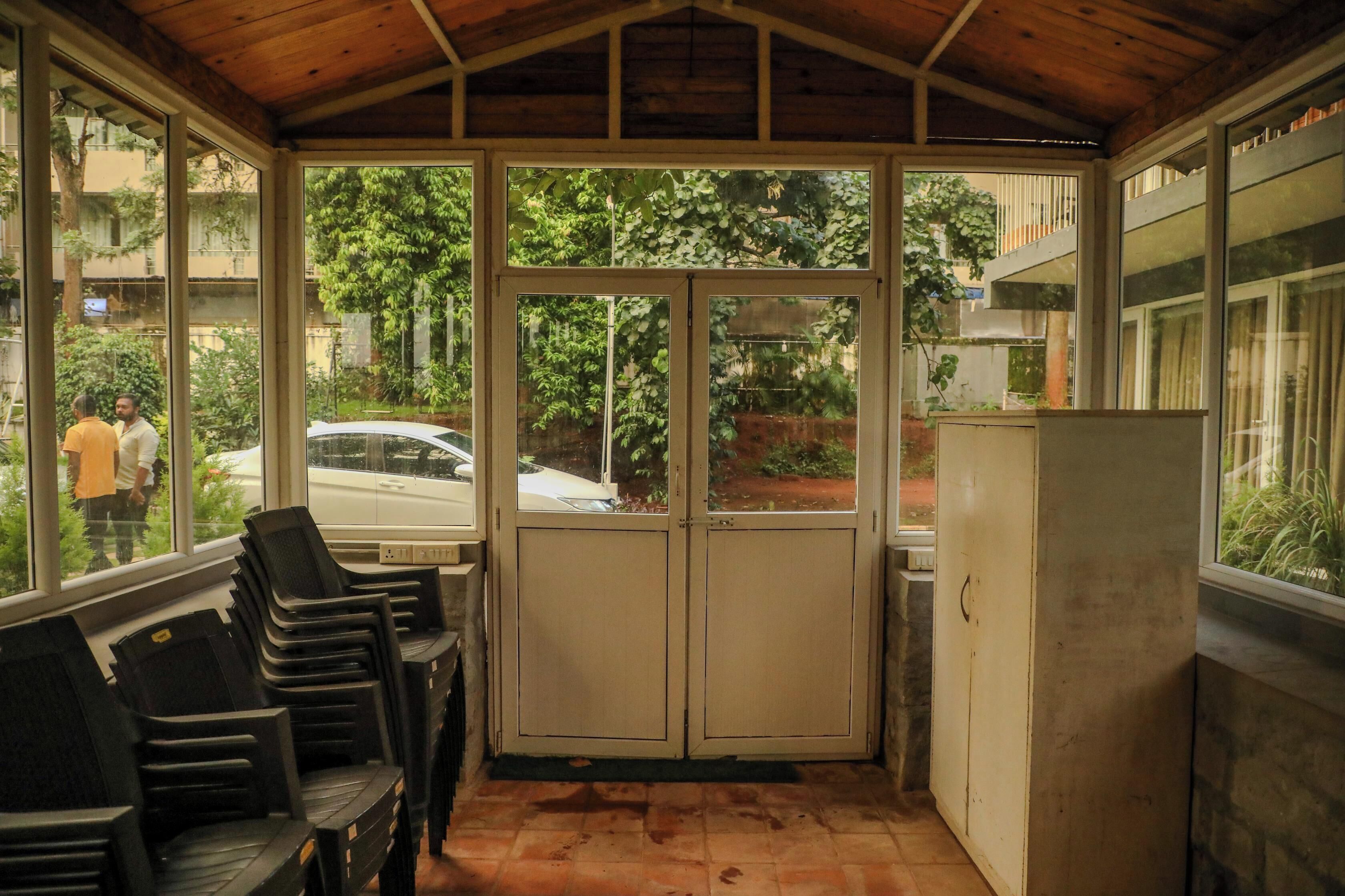 A covered outdoor area with a bench, a refrigerator, and a view of the street.