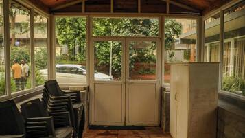 A covered outdoor area with a bench, a refrigerator, and a view of the street.