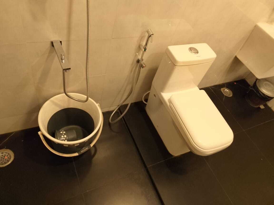 Ein Badezimmer mit Toilette, Dusche und Eimer.
