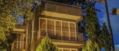 Un bâtiment moderne à deux étages, doté de balcons et entouré d’un espace verdoyant bien entretenu.