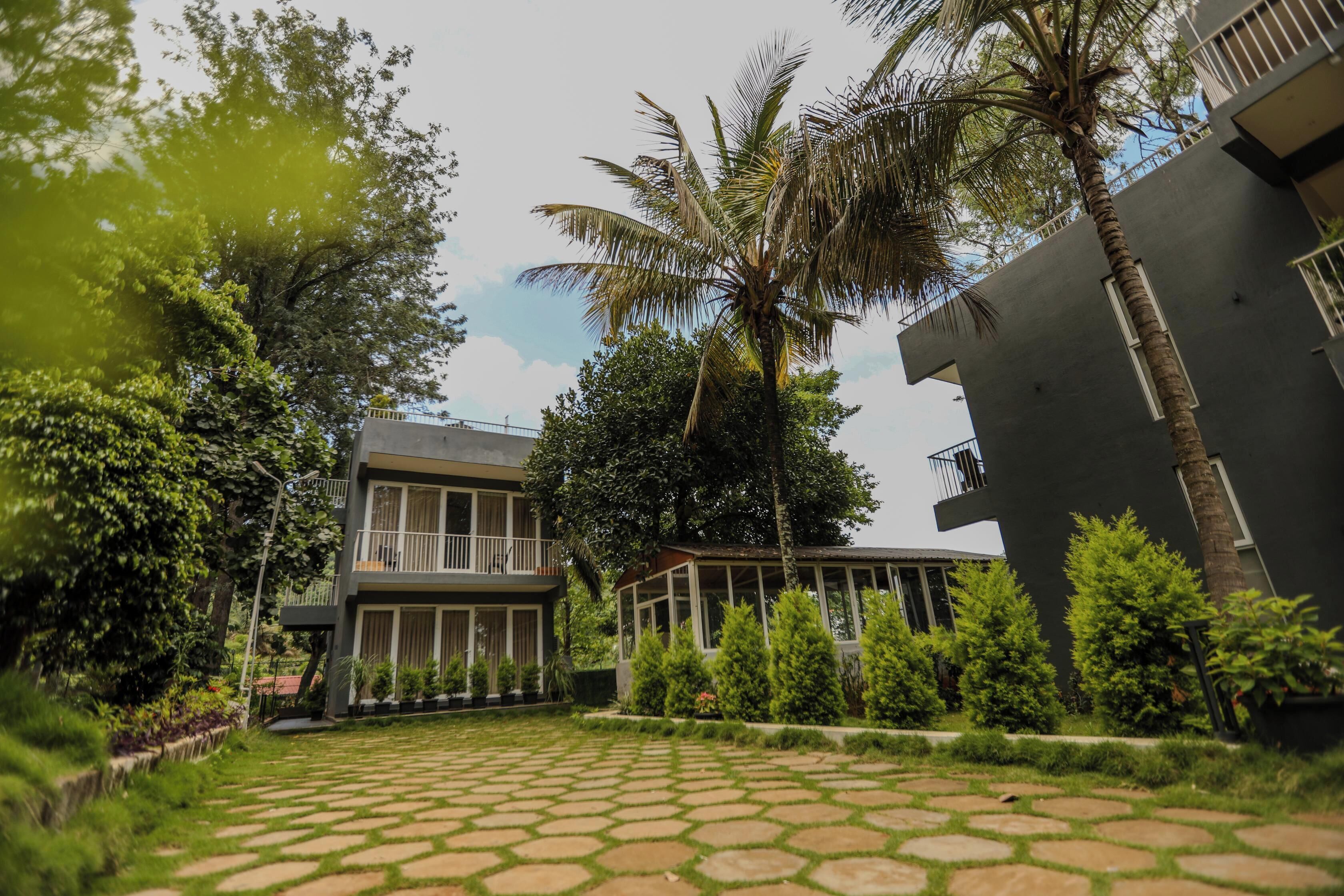 A modern building with a courtyard, palm trees, and a stone pathway.
