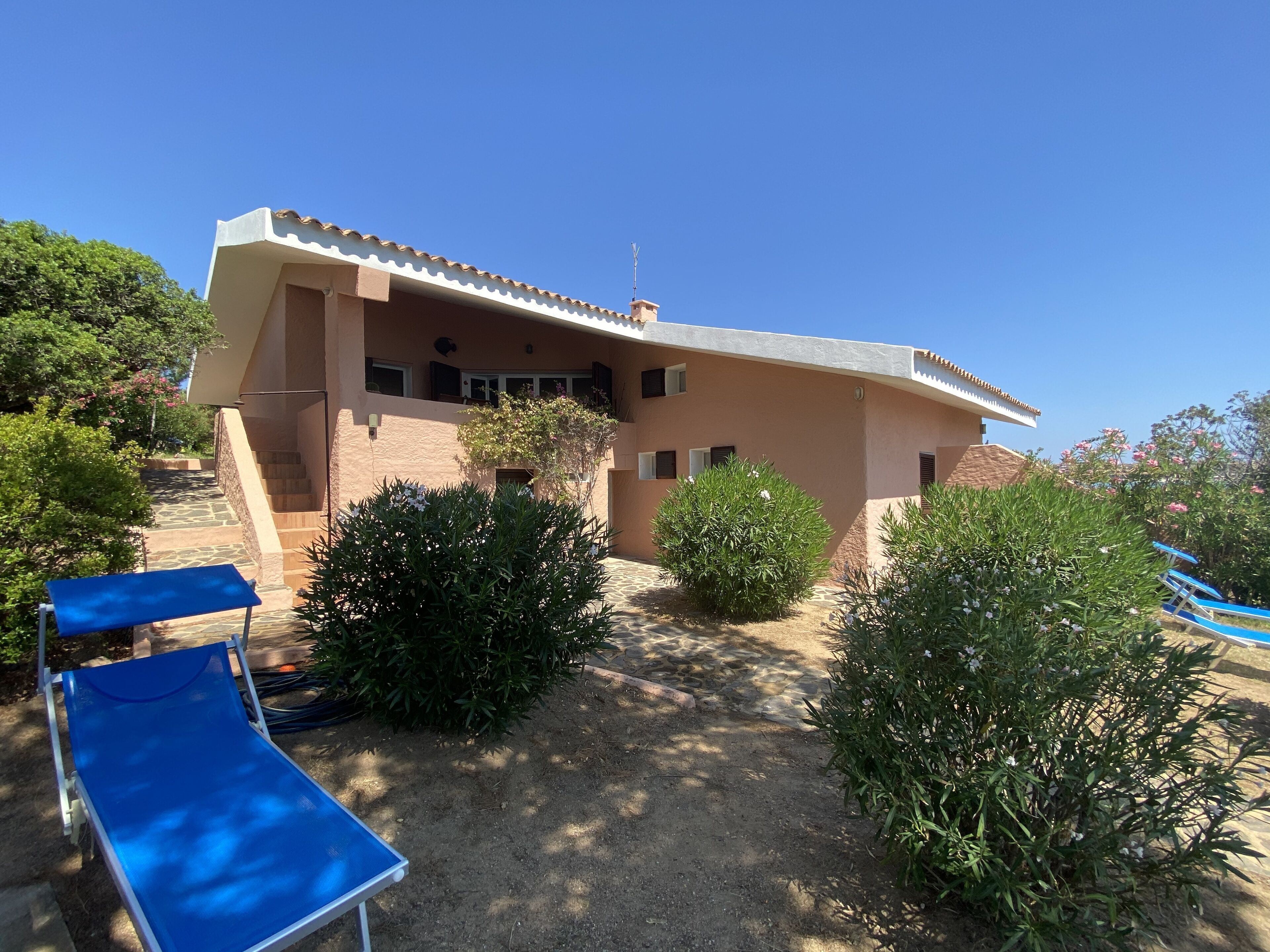 A two-story house with a balcony, a blue lounge chair, and a pool area.